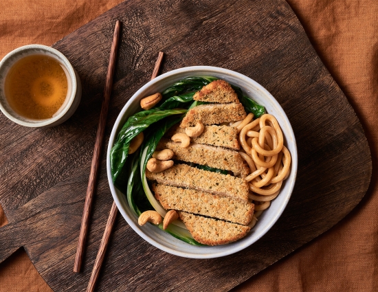 Cotoletta con noodles alla salsa di soia, bok choy (cavolo cinese) e anacardi