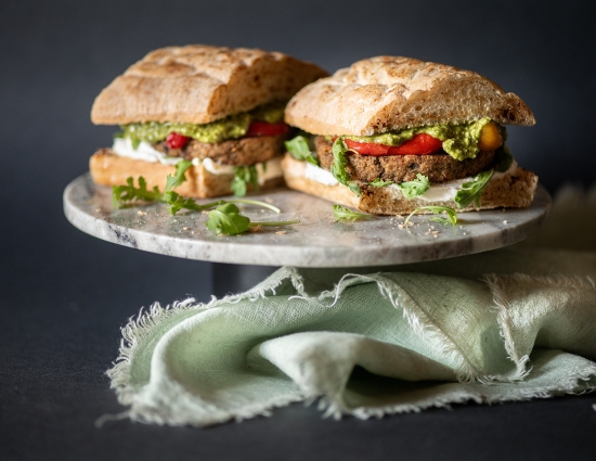 Sandwich con burger di melanzane, pesto, spalmabile vegetale, rucola e peperoni