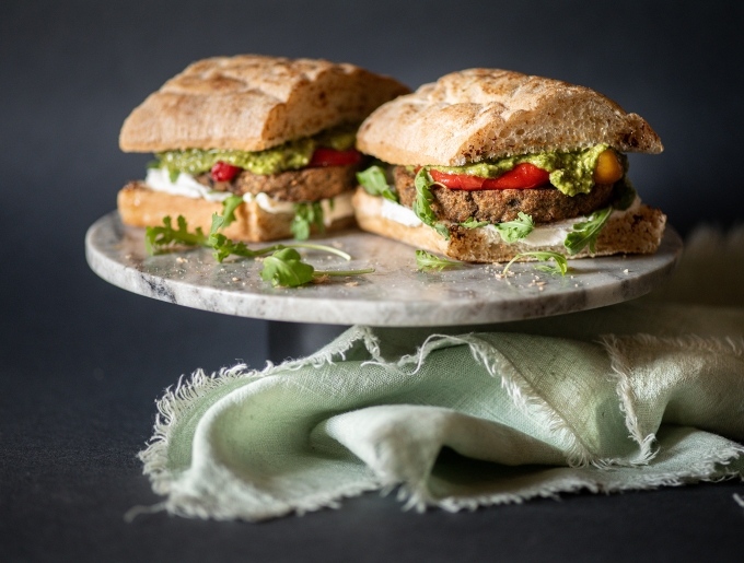 Sandwich con burger di melanzane, pesto, spalmabile vegetale, rucola e peperoni